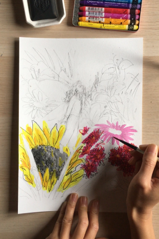 A hand painting a pink flower on paper using a brush and gouache.